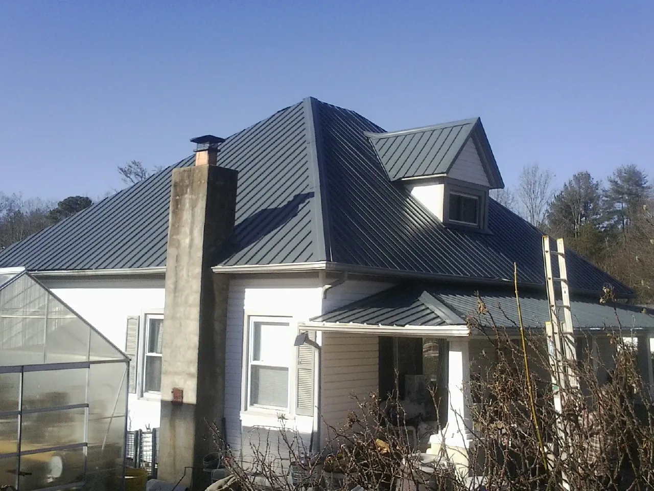 Dark blue standing seam metal roof on a white farmhouse with dormer — Slate & Tile Roof Repair by Roofing Brothers in South El Monte