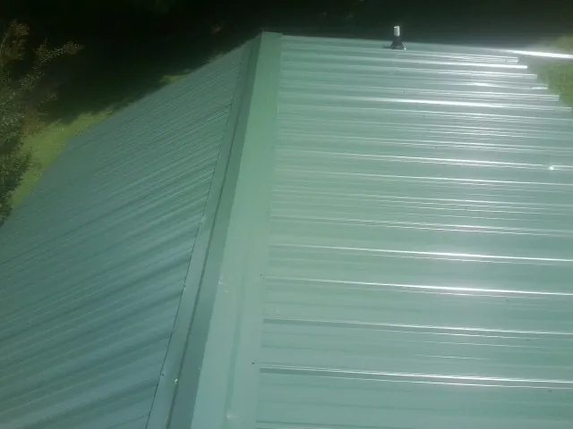 New green metal panels meeting at the ridge of a roof — Flat Roof Repair work by our crew in South El Monte