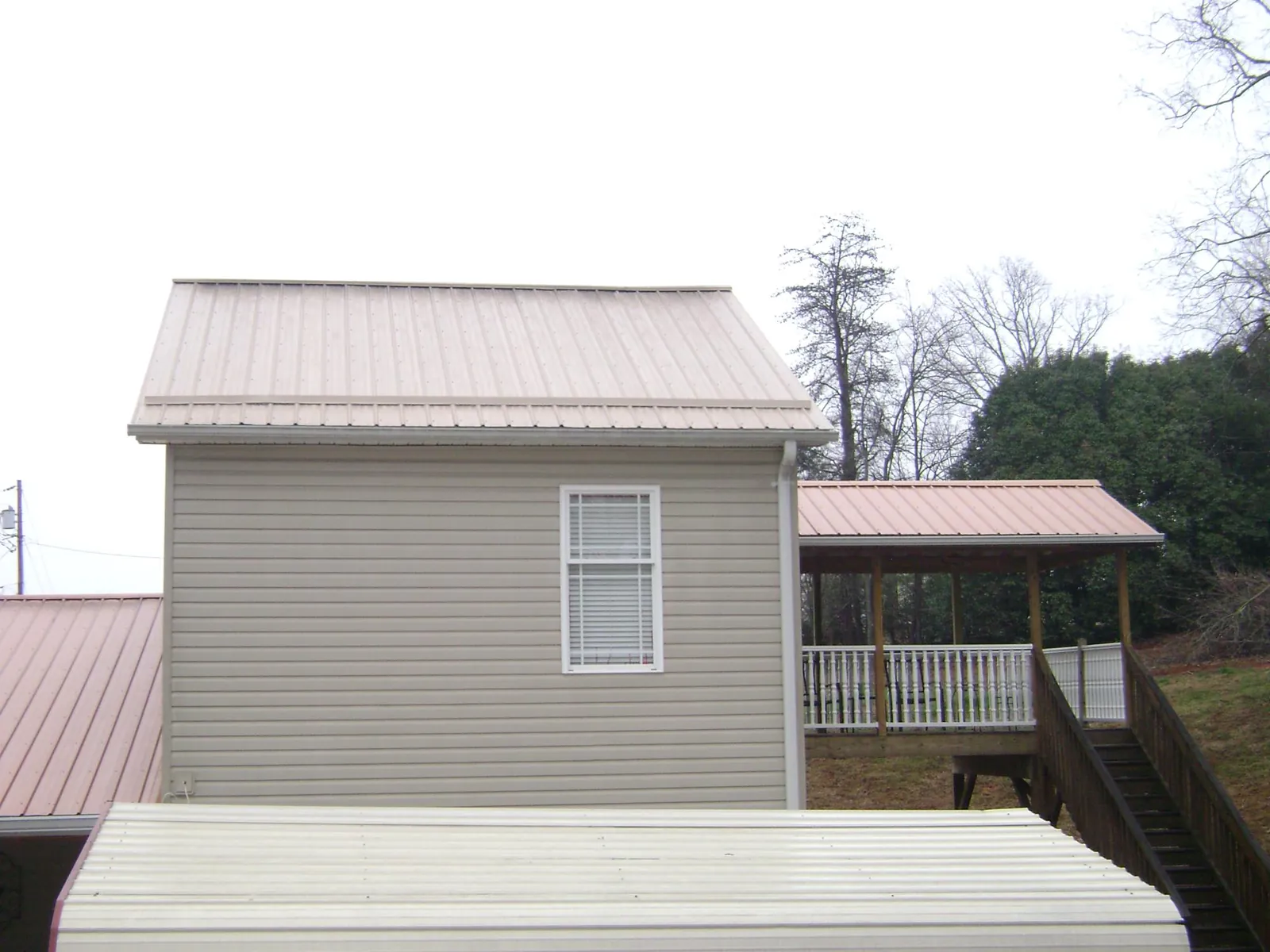 Tan metal roofs on a two story addition and attached porch, from a Roof Replacement job in South El Monte